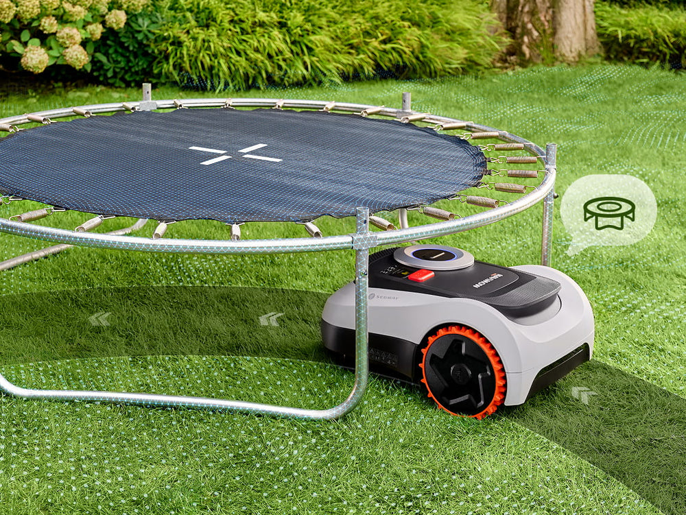 Segway Navimow robot lawn mower mows grass under a trampoline.
